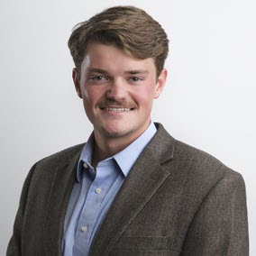 a man wearing a suit and tie smiling at the camera